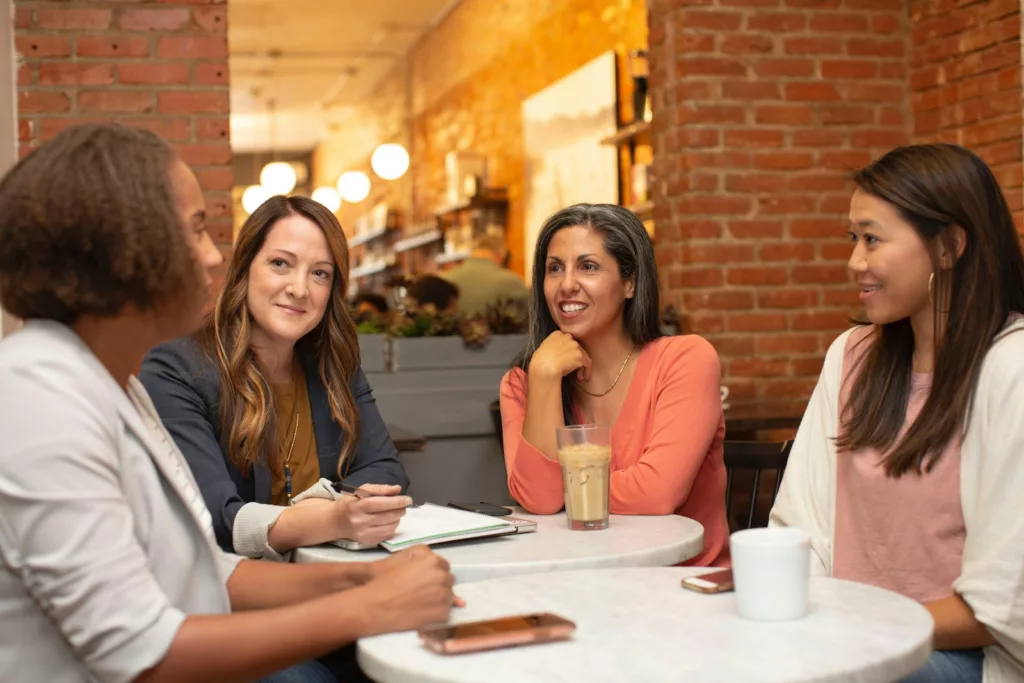 woman in black jacket sitting beside woman in white blazer developing good communication skills 